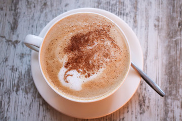 Cup of cappuccino coffee on wooden table.