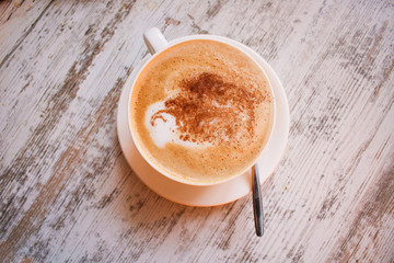 Cup of cappuccino coffee on wooden table.