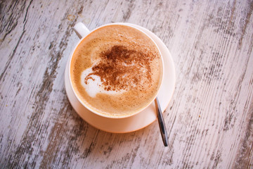 Cup of cappuccino coffee on wooden table.