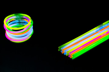 Colorful fluorescent light neon glow stick bracelet strap wristband on mirror reflection black...
