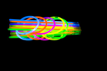 Colorful fluorescent light neon glow stick bracelet strap wristband and tubes on mirror reflection...