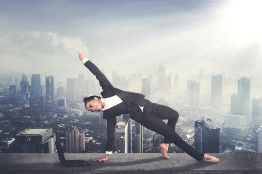 Businesswoman dances with a laptop on the rooftop - Powered by Adobe