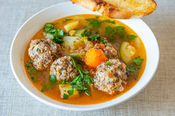 Mexican soup with meatballs and vegetables in a plate on a rustic background - Albondigas