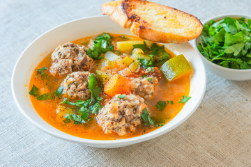 Mexican soup with meatballs and vegetables in a plate on a rustic background - Albondigas