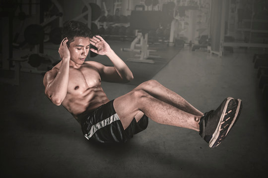 Muscular man doing crunches exercises on the floor