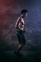 Muscular young man doing run exercises on studio