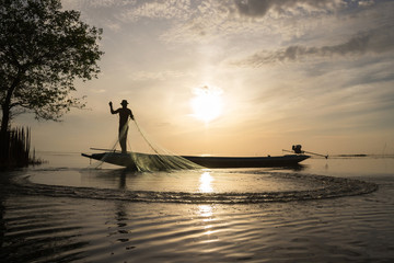 Silhouette of traditional fishermen throwing net fishing at sunrise time, livelihoods of fishermen at Pakpra, Phatthalung in Thailand