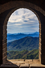 View onto a mountain range through a window in a watchtower of the Great Wall of China in the Mutianyu village, near Beijing