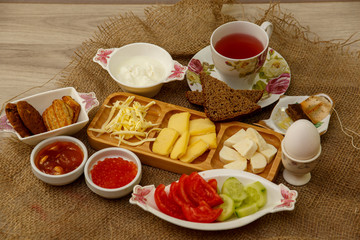 Natural breakfast consisting of cheeses, caviar, tomatoes, cucumbers, butter, eggs, rye bread and tea. The concept of tasty and natural food.