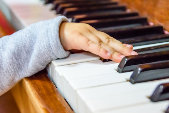 Child hand on the shiny piano keys