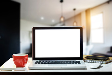 Front view of cup and laptop, smartphone, and tablet on table in office and background 