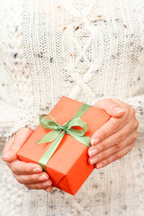 Woman holding a gift box tied with green ribbon in the hands