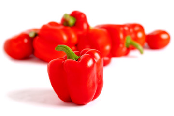 One sweet pepper, red, on a blurred background of vegetables, light on the right.