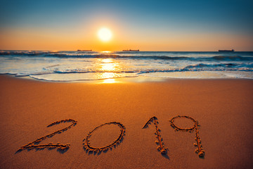 Sea sunrise. Happy New Year 2019 lettering on the sand.