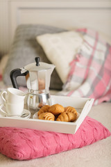 Fototapeta na wymiar Breakfast in bed. On a white wicker tray there is a coffee maker, coffee cups and croissants.