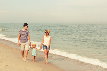 Happy family! Dad, mother and daughter are walking along the sea. Copy space.