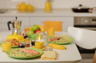 Breakfast time. Omelet with greens and sausages. Croissants and orange juice, jam. Coffee with cream or milk. Fruits - bananas, red and green apples.