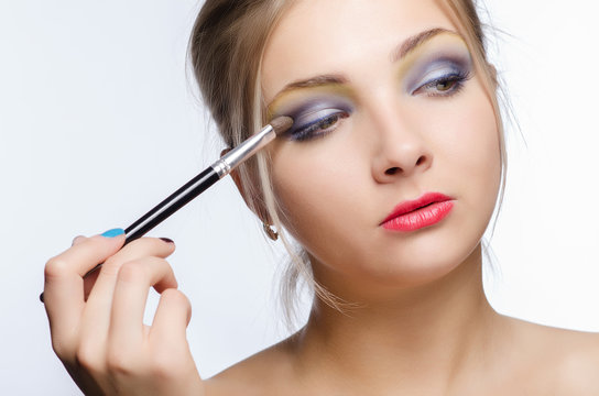 Make-up artist apply beauty makeup on the face of a beautiful girl.