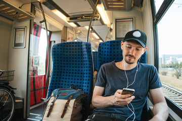 A young man listens to a music or podcast while traveling in a train.