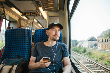 A young man listens to a music or podcast while traveling in a train.