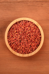 Fototapeta na wymiar Red rice, shot from above in a wooden bowl on a dark rustic background with copy space