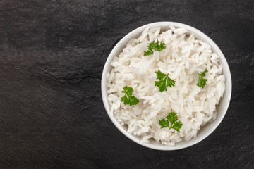 A photo of a bowl of cooked white long rice, shot from above on a black background with a place for text