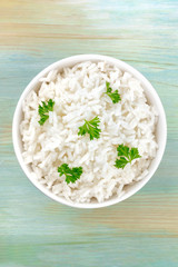 A bowl of cooked white long rice, shot from above on a teal blue background with a place for text