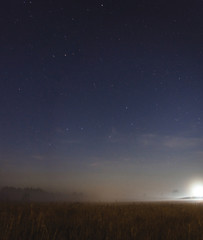 Obraz na płótnie Canvas Moon setting in a misty field on a starry night