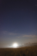 Moon setting in a misty field on a starry night