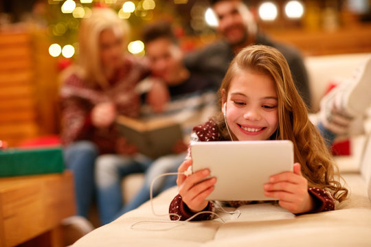 little girl with headphones lying and using a tablet on Christmas day.