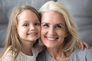 Happy old elderly grandmother hugging little smiling grandchild girl, loving senior grandma...