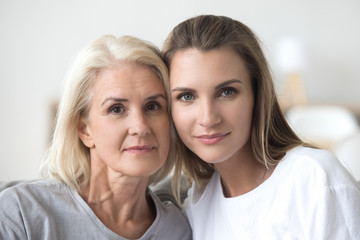 Headshot portrait of senior older mother and young daughter, two women of different age generations bonding looking at camera, love, care and support in mom and adult child family relations concept