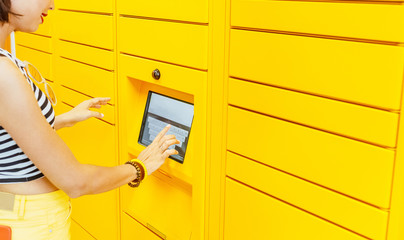 Woman client using automated self service post terminal machine or locker to deposit the parcel for...