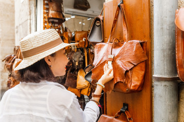 Young woman shopping and chooses bag at shop