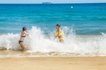 Young woman tourist in swimsuit having fun in wavy waters of Mediterranean sea, storm weather at the sea concept