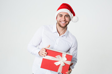 Handsome man in a Santa hat with a gift box in his hands on a white.