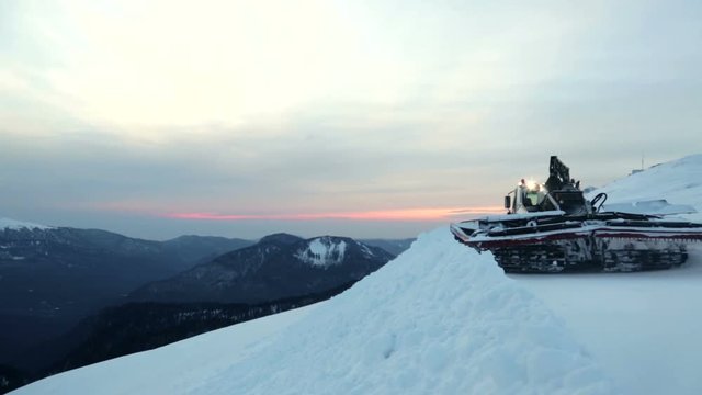 Snowcat runs on the mountain peak