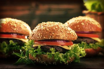 Hamburger with beef meat and fresh vegetables on wooden background