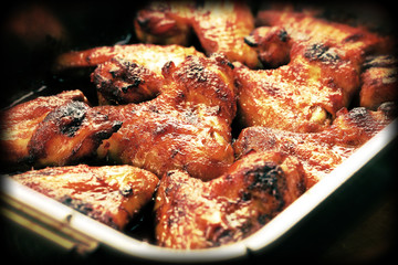 Roasted chicken wings with baked potato on the table, close up vintage view