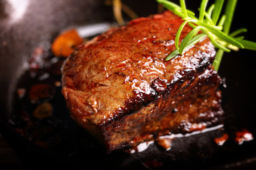 Juicy beef steak and herbs spices on cast iron skillet pan