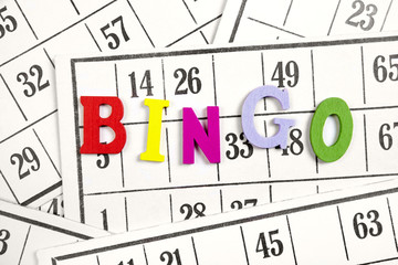 The word bingo made of wooden letters on bingo cards background.