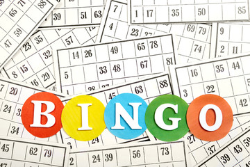 The word bingo made of wooden letters on bingo cards background.