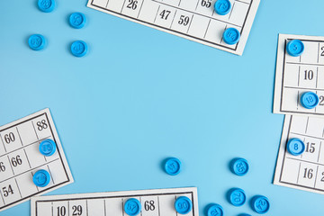 Bingo balls and cards on blue background with copy space.