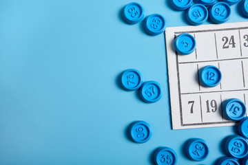 Bingo balls and cards on blue background with copy space.