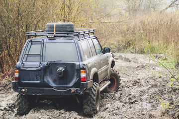 Offroad car runs through large swamps. Shrazjuk after rain. Hard road. Gory Dirty wheels.