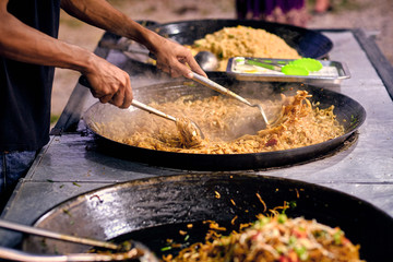 Fried noodles in a wok. Asian, Indian and Chinese street food. Food court on local market of Langkawi island, Malaysia..Traditional asian street food.