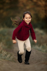 Fototapeta premium little cut girl playing in autumn park