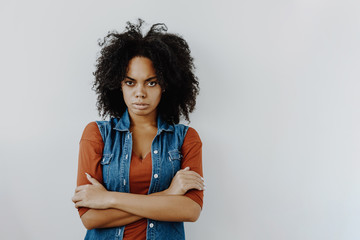 Woman portrait. Cheerful Afro American girl in casual clothes is looking seriously at camera while...