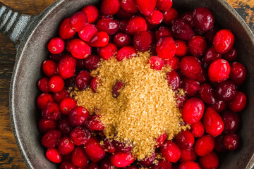 Cooking of traditional cranberry sauce. Black cast-iron skillet, top view, closeup