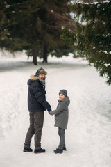 Happy father with his son walks through the park in the snowy winter weather